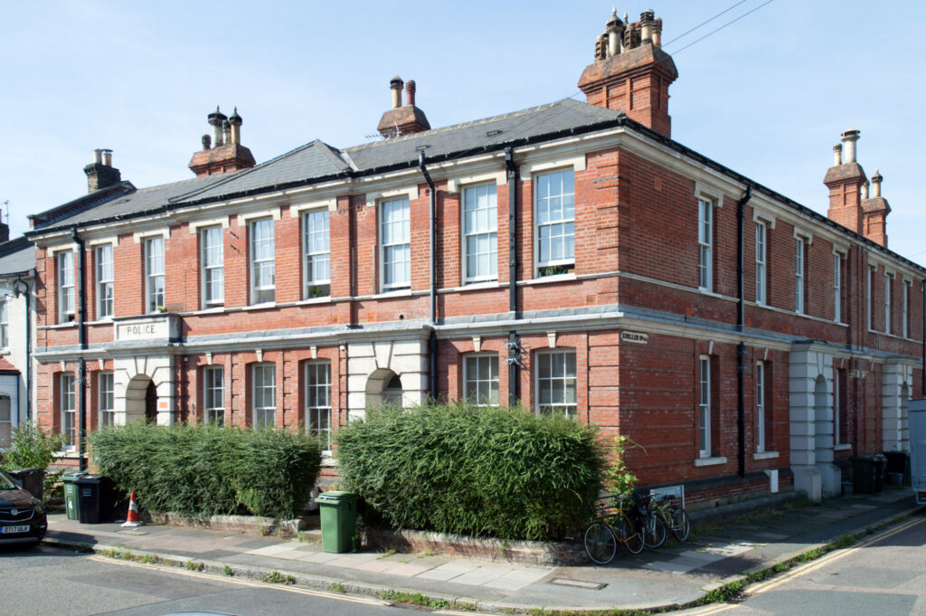 A photograph of a red brick building on a corner with windows on both sides.